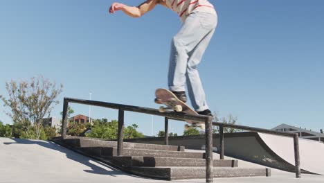 Low-section-of-caucasian-man-riding-and-jumping-on-skateboard-on-sunny-day