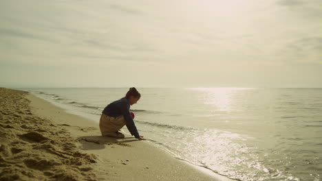 little kid touching sea waves on sunset beach. cute girl playing sand at ocean.