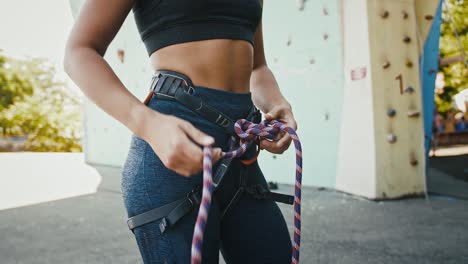 primer plano de una mujer profesional de alpinismo atando un nudo de una cuerda de escalada