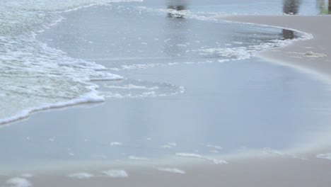 a close up shot of waves wash over the sand