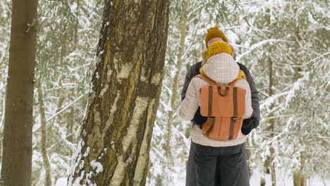 couple in winter clothes hugging in winter forest