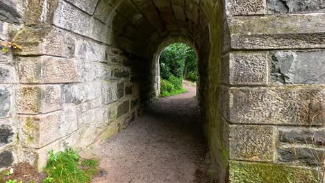 path through stone tunnel into lush greenery