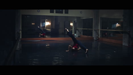 a young woman practices modern dancing and ballet in a moody room full of mirrors