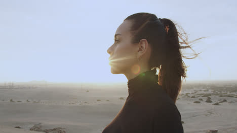 primer plano de la cara lateral de una hermosa mujer vestida de negro con el pelo atado en medio del desierto a la luz de la tarde