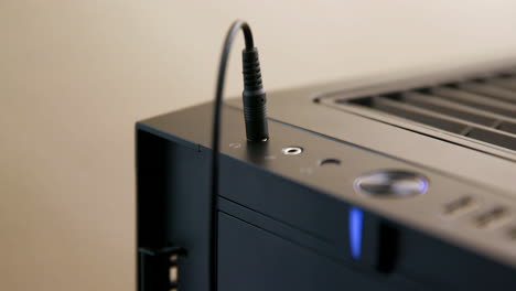 el hombre enchufa y luego desenchufa el cable de los auriculares en el conector de la computadora de escritorio
