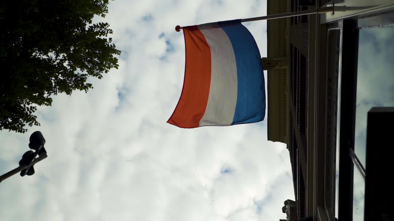 The Dutch flag blowing in a light breeze, cloudy sky.