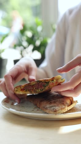mujer comiendo un sándwich de pita a la parrilla
