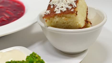 borscht with cake, cream, and green sauce