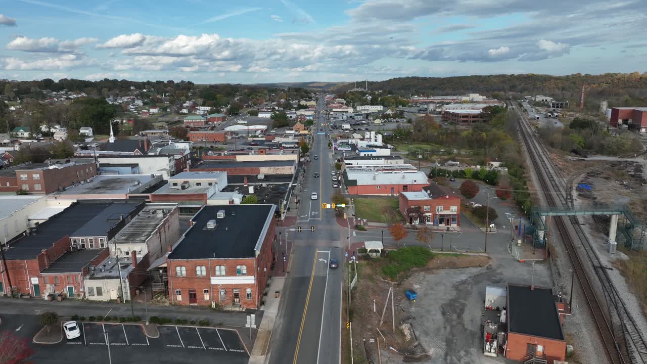 Descending drone shot of main street in historic american town on sunny autumn day. Railroad beside city in Virginia. Rooftops of houses and homes. Wide shot.