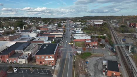 descending drone shot of main street in historic american town on sunny autumn day. railroad beside city in virginia. rooftops of houses and homes. wide shot.
