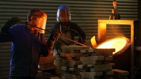 trabajador masculino mezclando metal moldeado en un contenedor en el taller 4k