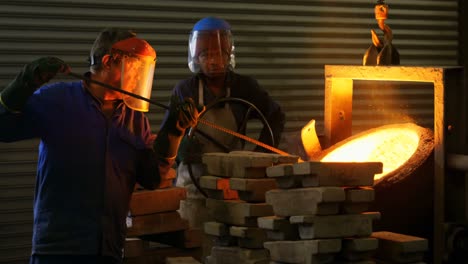 male worker mixing molted metal in container at workshop 4k