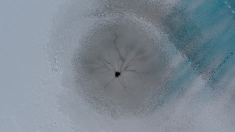 round hole in a frozen lake. a natural hole from an underwater spring