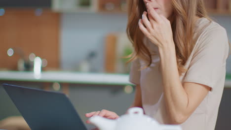 businesswoman snacking in the kitchen while reading email