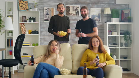 Girls-sitting-on-couch-eating-popcorn-while-watching-tv