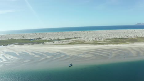 Drone-Vuela-Por-Una-Playa-Con-Un-Bote-En-La-Orilla