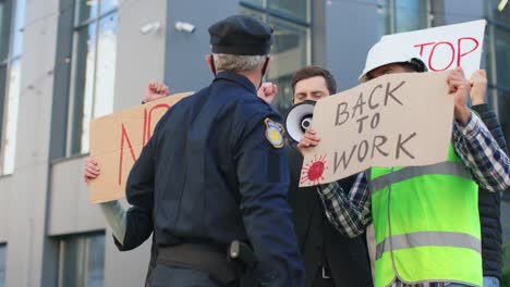 policjant rozmawia z grupą ludzi podczas demonstracji przeciwko covidowi 19 na ulicy