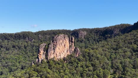 aerial footage captures the iconic nimbin rocks surrounded by lush greenery under clear blue skies