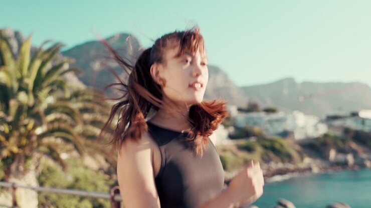 Woman running by ocean for fitness challenge
