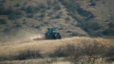 vista de teleobjetivo de un tractor arando en un campo en un día cálido y soleado con una colina en el fondo