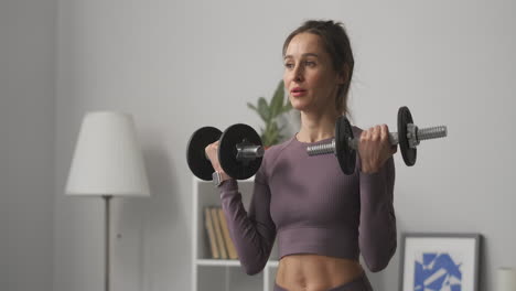 mujer deportiva cansada está levantando pesas entrenando en un apartamento durante el día retrato medio de una deportista en casa durante el entrenamiento diario