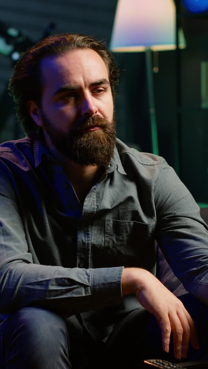 Vertical video Man enjoying bowl of popcorn and smiling while watching cable programs on TV