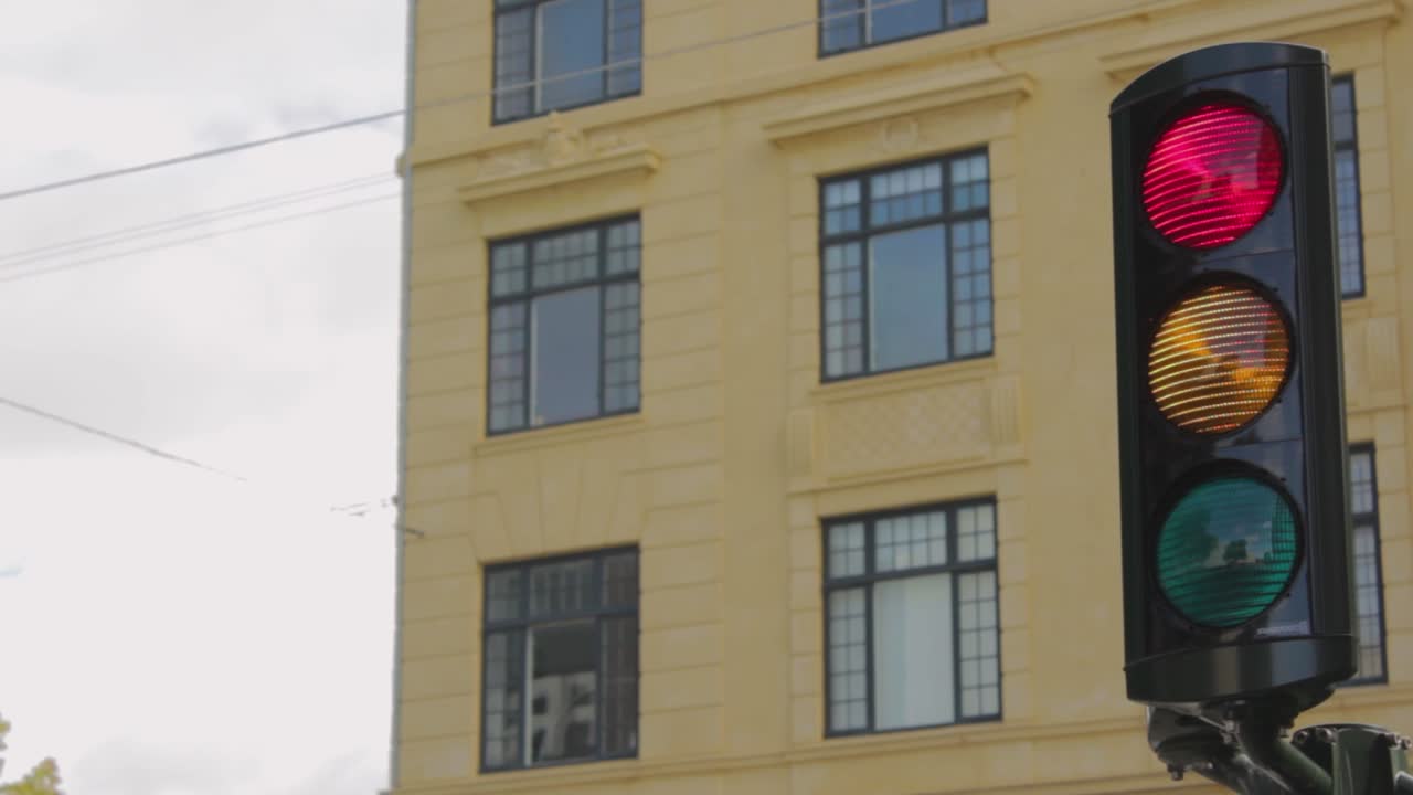 Red traffic light regulates the road. Close-up moving from left to right. Traffic regulations and driving safety. Building on background, Copenaghen, Denmark