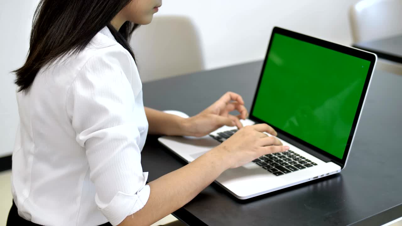 4K : Happy Asian business woman typing on a laptop computer with a key green screen