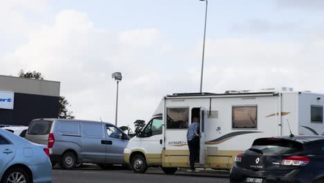 autocaravana estacionada con coches cercanos y persona de pie