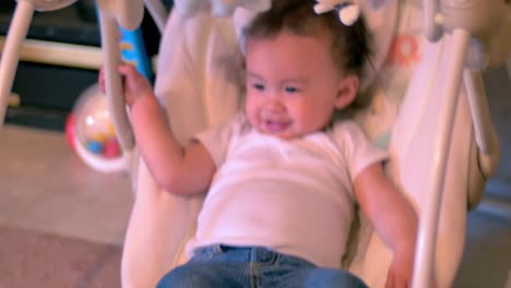 a toddler sitting in a baby swing and smiling