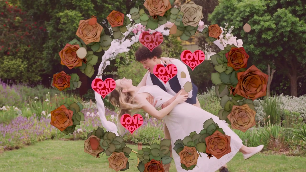 Par omfavner hinanden i en blomsterkrans med roser og neon 'LOVE YOU'-hjerter, danser til et bryllup.