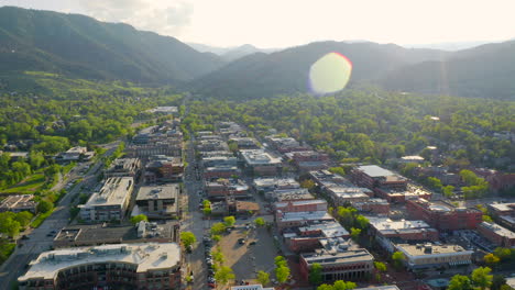 Toma-Aérea-De-Una-Hermosa-Vista-Montañosa,-árboles-Verdes-Brillantes-Y-Calle-Perla-En-El-Centro-De-Boulder-Colorado-Durante-Una-Puesta-De-Sol-Vespertina-Con-Luz-Cálida-En-La-Ciudad-Montañosa-Rocosa-Y-El-Paisaje-De-Verano