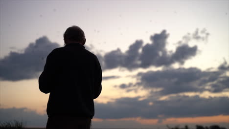 Man-watching-birds-at-sunset