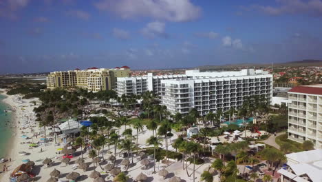 highrise hotels with palm trees blowing in the wind along the beach in aruba