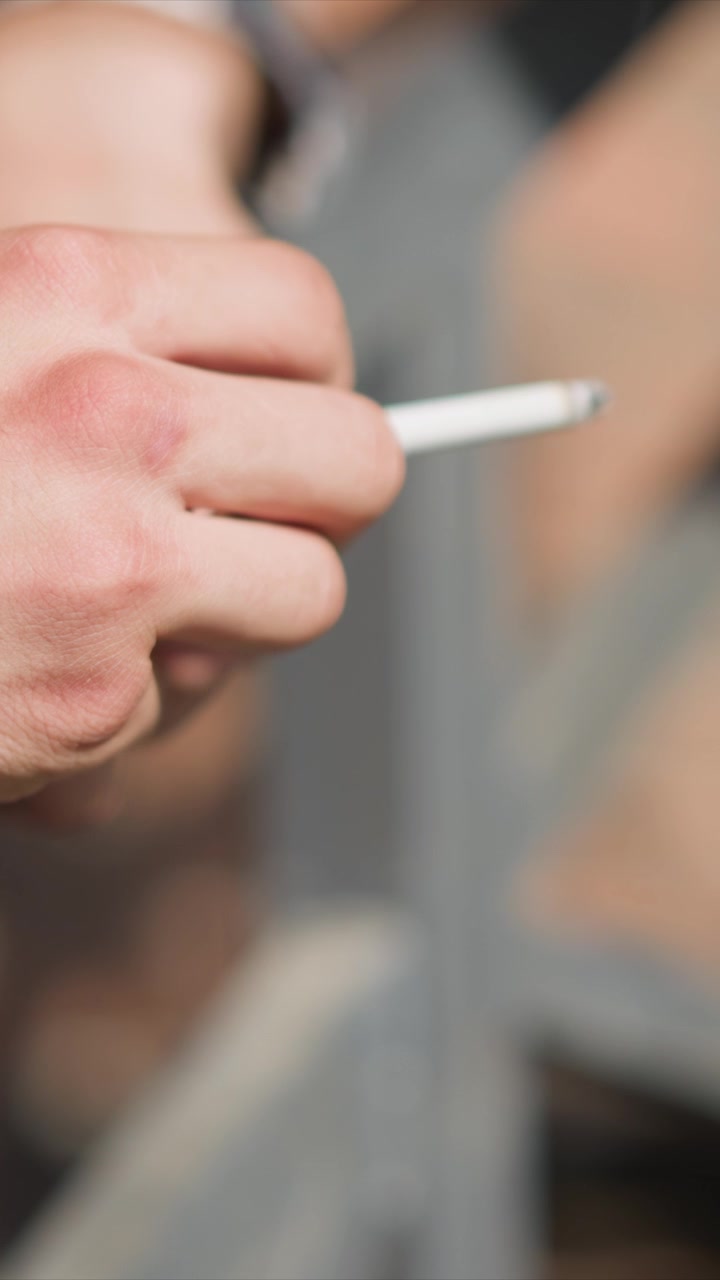 Primo piano delle mani di un uomo con segni rossi e irritazione visibili, che tengono o con un oggetto. Il dettaglio della texture della pelle è prominente, mostrando un posizionamento costante della mano contro una luce soffusa.