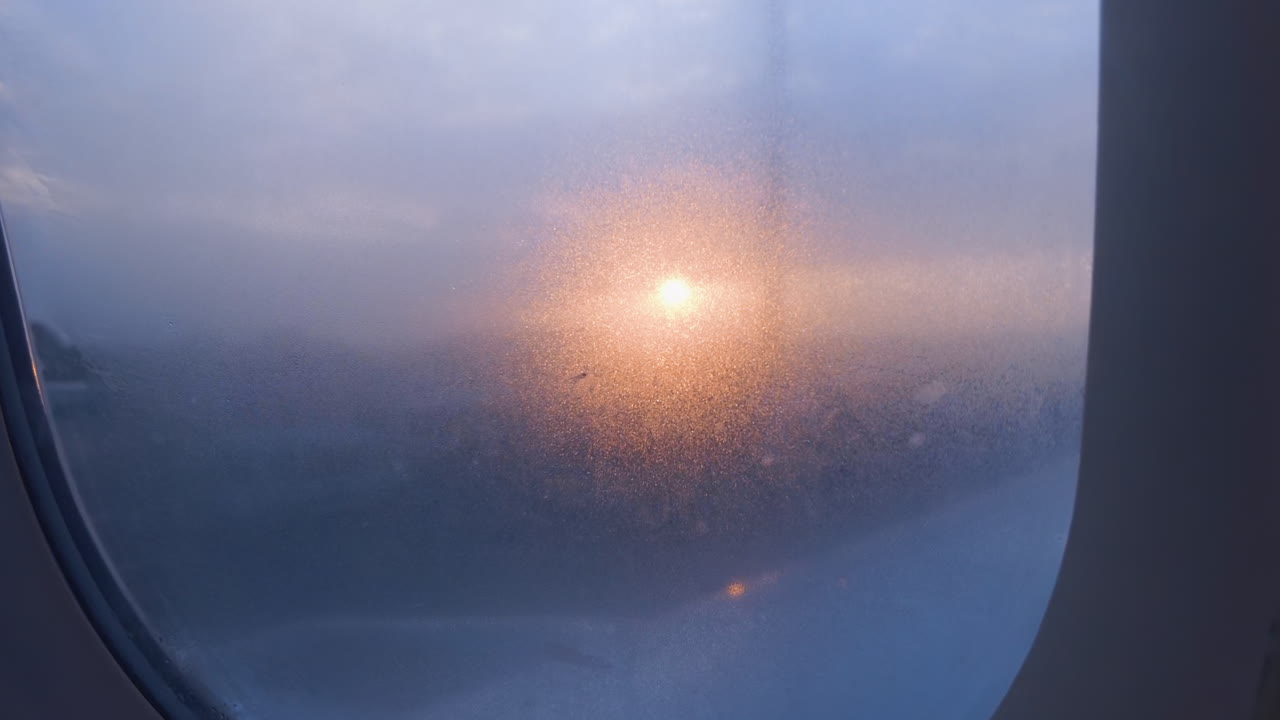 Zonsopgang door een vliegtuigraam met condensatie