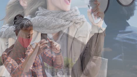 Animation-of-african-american-female-friends-wearing-face-masks,-taking-photos-over-caucasian-woman