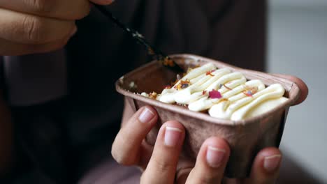 persona comiendo un pastel pequeño con crema y flores comestibles