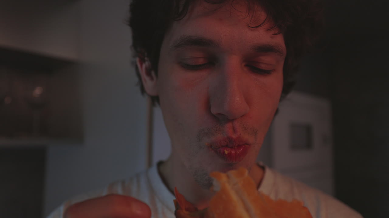 Close-up of a Young Man Enjoying a Sandwich