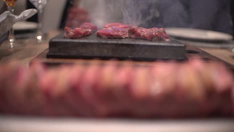 friends eating at restaurant celebrating birthday in dinning room, toasts, cheers and preparing their own meat at hot stone