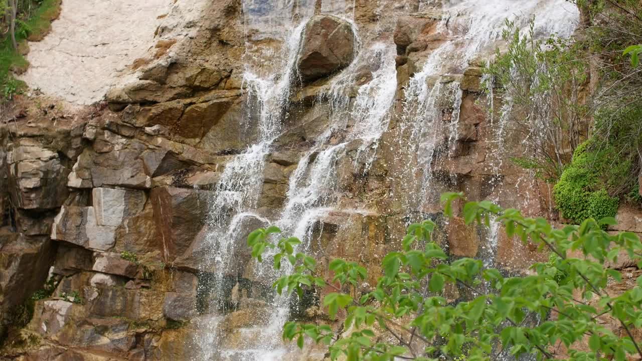 hermosa cascada desde un acantilado en el bosque. 4k video de agua que fluye, arroyo que fluye entre las piedras. arroyo en el bosque