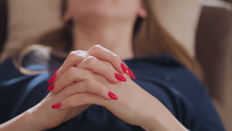 close up view of patient resting while moving hands expressively during calm therapy session, showing red painted nails, natural skin texture, and subtle gestures that reflect inner thought