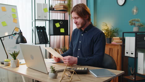 focused office worker man working with schedules financial graphics while using calculator laptop