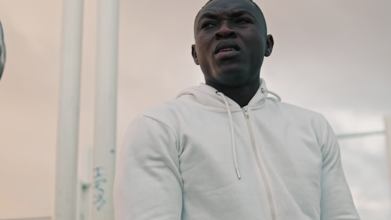 Young Black Man Stretching on Gymnastic Rings at Outdoor Gym