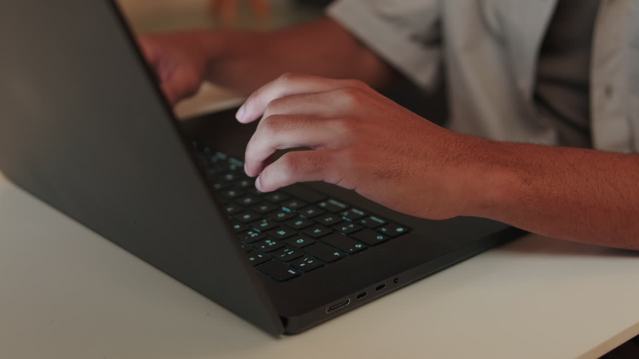 ノートパソコンのキーボードをタイピングする手のクローズアップ