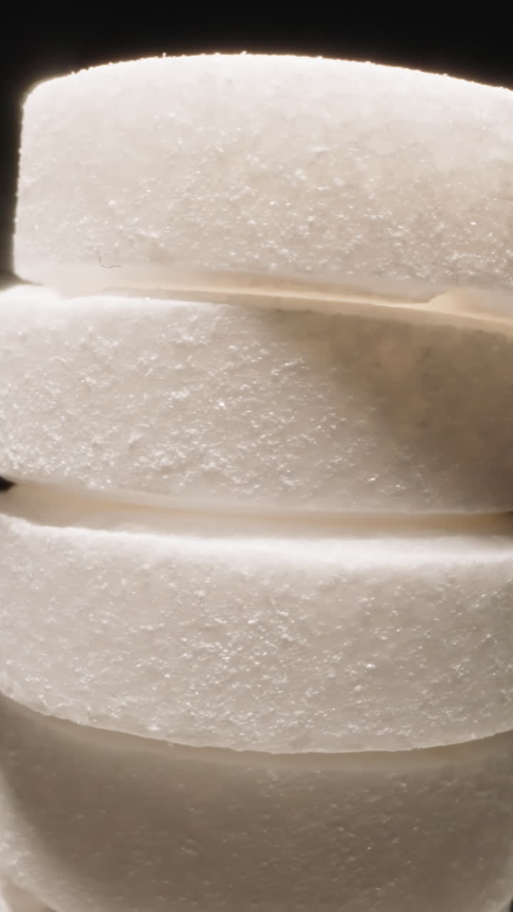 White round pills put in stack rotating at bright light on black background. Effective medication for health treatment. Pharmacy production macro