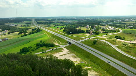 Aerial-view-of-a-highway-intersection-in-a-rural-area-with-green-fields-and-forests