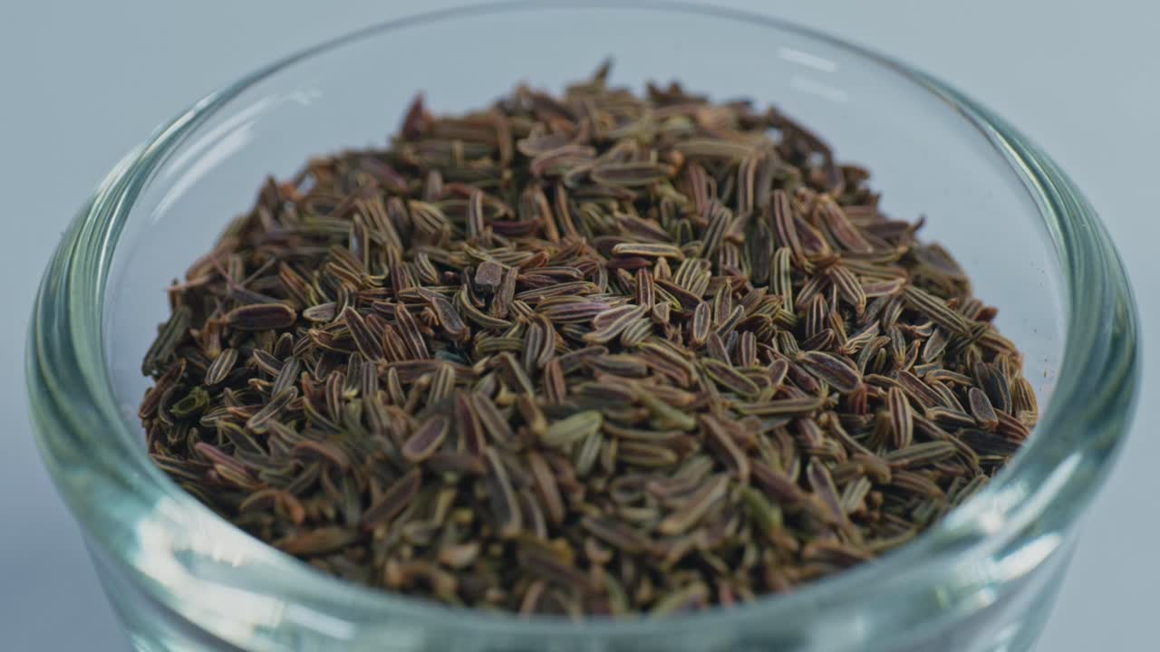 caraway seeds or Shah jeera in small glass bowl, 4k, parallax shot.