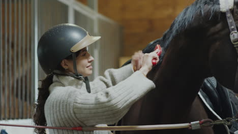 female stable worker brushing horse mane