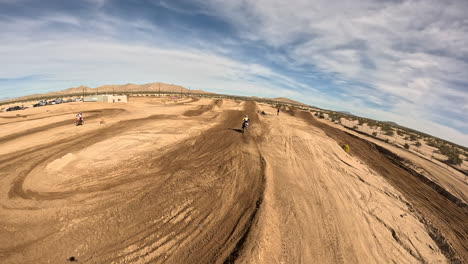 off-road racing motorcycle taking a hairpin turn then going over a jump on a off-road racecourse - first person drone view